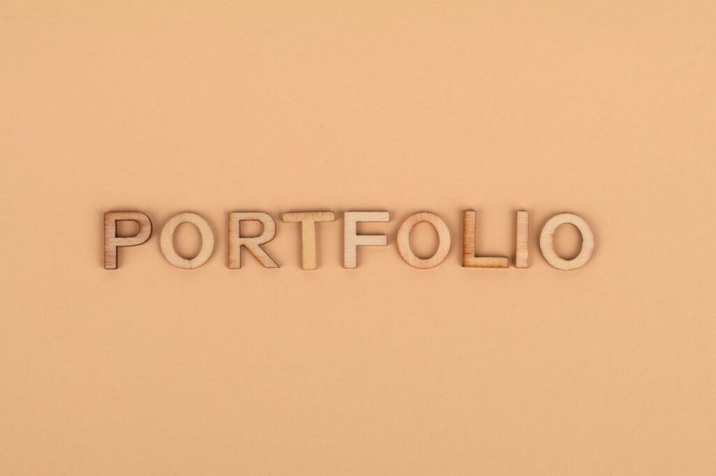 Close-up of wooden letters spelling 'PORTFOLIO' on a yellow background, offering creative copyspace.