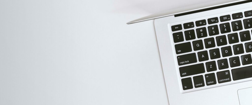 Aerial view of a sleek laptop keyboard on a clean, white surface, ideal for tech backgrounds.